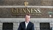 En smilende mand foran Guinness-skilt