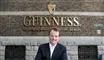 En smilende mand foran Guinness-skilt