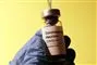 glasflaske med vaccine med gul baggrund