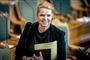Inger Støjberg i Folketingssalen med et smil til kameraet.