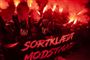 demonstranter med romerlys og banner med påskriften "Sortklædt modstand" 