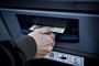 En mand hiver hundrede kroner ud af en pengeautomat. 