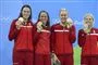fire svømmere i røde dragter med medaljer i hånden