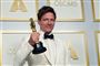 Thomas Vinterberg i hvid smoking med den berømte guldstatuette i hånden. 