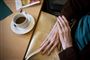 person sidder ved bord med en kop kaffe