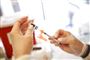 person står med kanyle og vaccineglas
