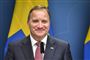 En mand i jakkesæt med et svanesk flag i baggrunden