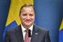 En mand i jakkesæt med et svanesk flag i baggrunden