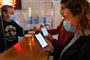Folk i en bar med mundbind og smartphones åbne