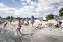 Børn og voksne i strandkanten.