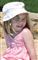 Feriebillede af en smilende Madeleine McCann med bøllehat og lyserød badedragt.