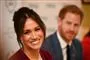 Meghan Markle med et stort smil og Harry i baggrunden.
