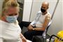 Magnus Heunicke med den ene arm ude af trøjen og et plaster på skulderen efter vaccinationen