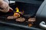 person griller bøffer på gasgrill 