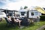 Folk sidder omkring en campingvogn