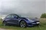 En blå Tesla og en mørk himmel