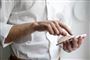 Mand står og taster på sin mobiltelefon