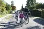 En far cykler med to små børn - alle bærer hjelm.