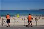 To mænd i orange dragter ved en strand