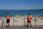 To mænd i orange dragter ved en strand