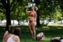 Eb kvinde i bikini i en park hun hælder koldt vand ud over sig.