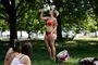 Eb kvinde i bikini i en park hun hælder koldt vand ud over sig.