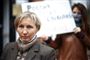 en blond kvinde med protest-skilt bagved