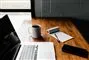 Arbejdsbord med computer, kaffe og notesblok