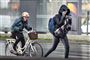 En cyklist og en fodgænger strider sig gennem blæs og regn