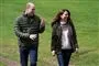 Prins William og Kate i jeans, sweatre og windbreaker jakker på en græsplæne. De griner. 