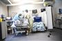 to hospitalsansatte står ved seng med patient