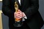 En mand med en Oscar statuette mellem begge hænder.
