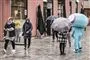 Regn på en gade og folk med paraplyer