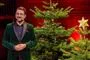en mand med skæg ved et juletræ