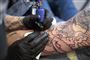En mand bliver tattovret på sin underarm. Tattovøren har handsker på.
