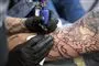En mand bliver tattovret på sin underarm. Tattovøren har handsker på.