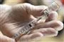 person står med kanyle og vaccineglas