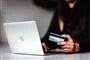 person sidder ved computer med kreditkort i hånden
