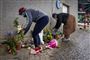 Folk lægger blomster ved en mur