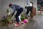 Folk lægger blomster ved en mur