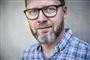 Lasse RImmer med store sorte briller kigger direkte ind i linsen. 