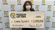 En kvinde med mundbind og en kæmpestor check foran sig.