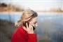 En kvinde i rød sweater taler i mobiltelefon udenfor 