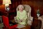 Dronning Elizabeth smiler i en stol
