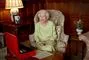 Dronning Elizabeth smiler i en stol