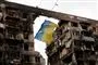 ukrainsk flag foran en ødelagt bygning