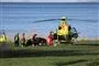 En redningshelikopter og redningsfolk ved en græsplæne ved havet