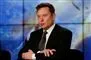 Elon Musk sidder med armene over kors og ser sur ud. 