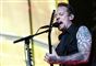 Michael Poulsen på scenen han synger ind i en mikrofon. 