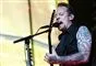 Michael Poulsen på scenen han synger ind i en mikrofon. 